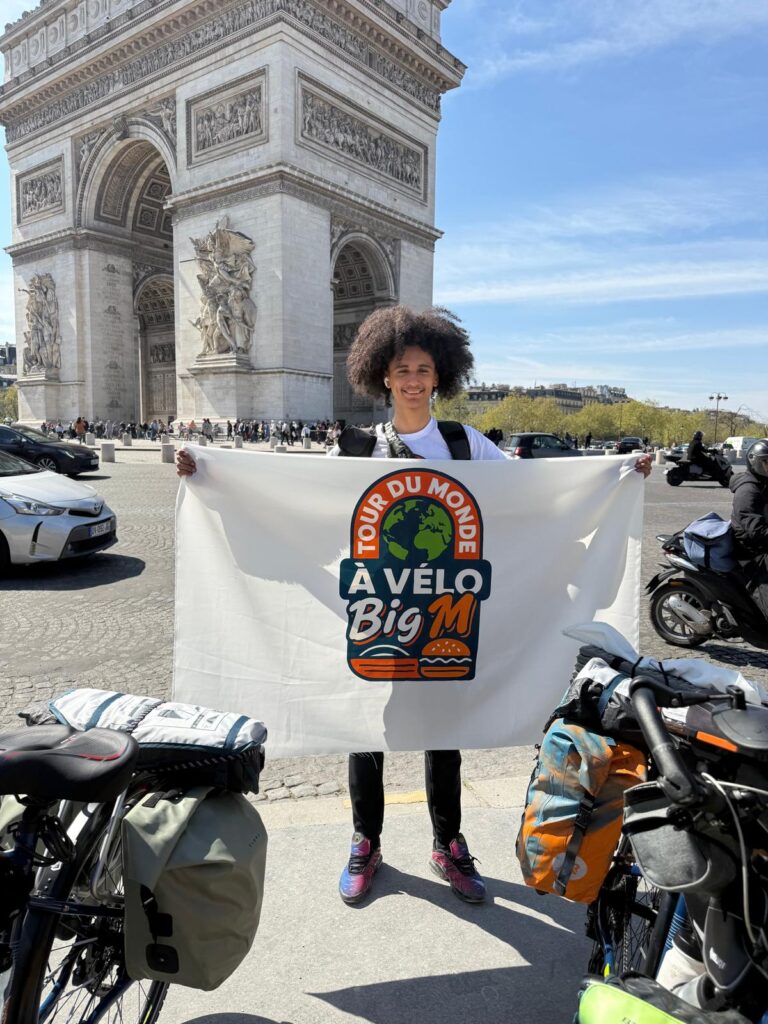 Personne avec un drapeau Big M devant l'arc de triomphe